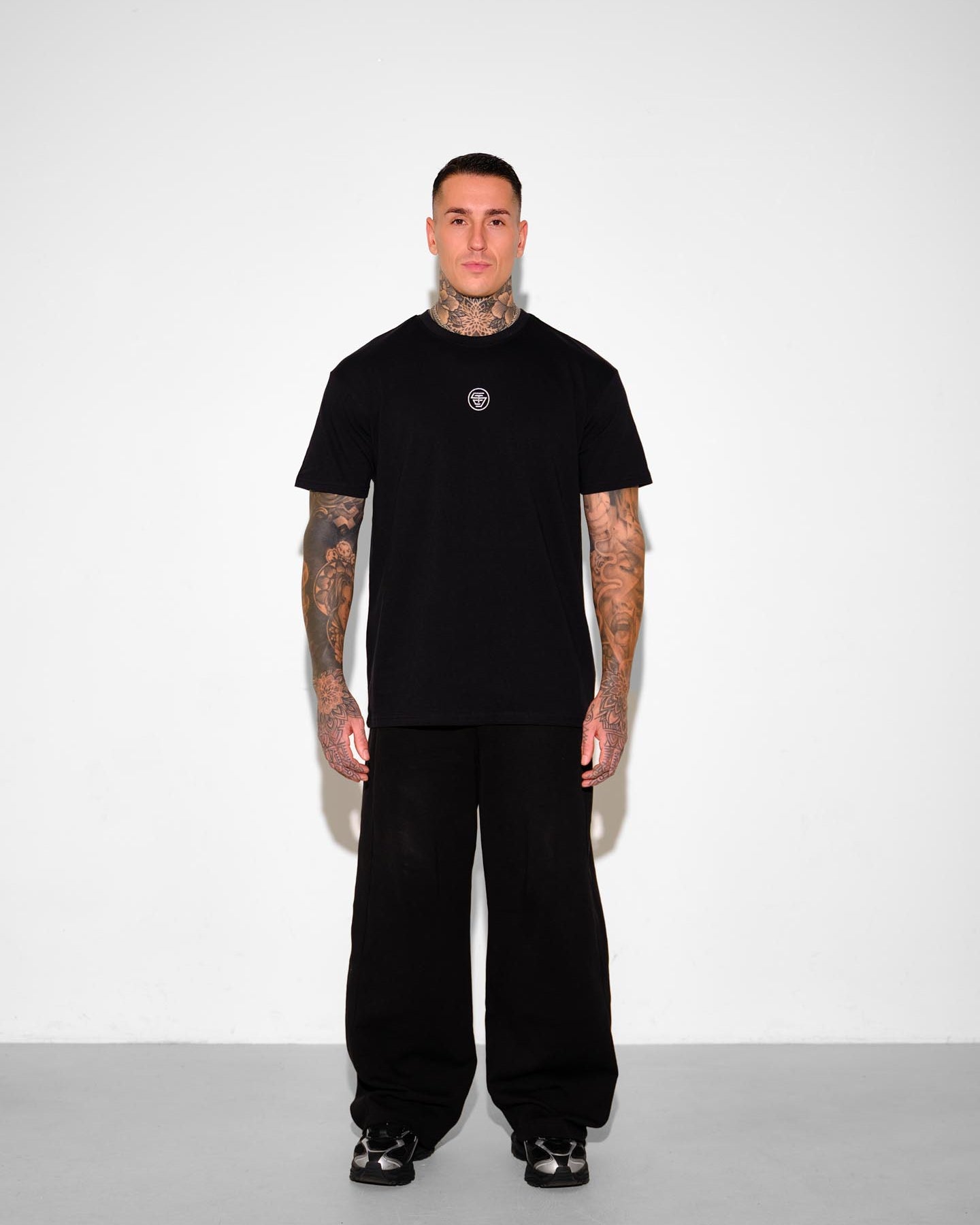 Person wearing a black t-shirt and pants with a white background