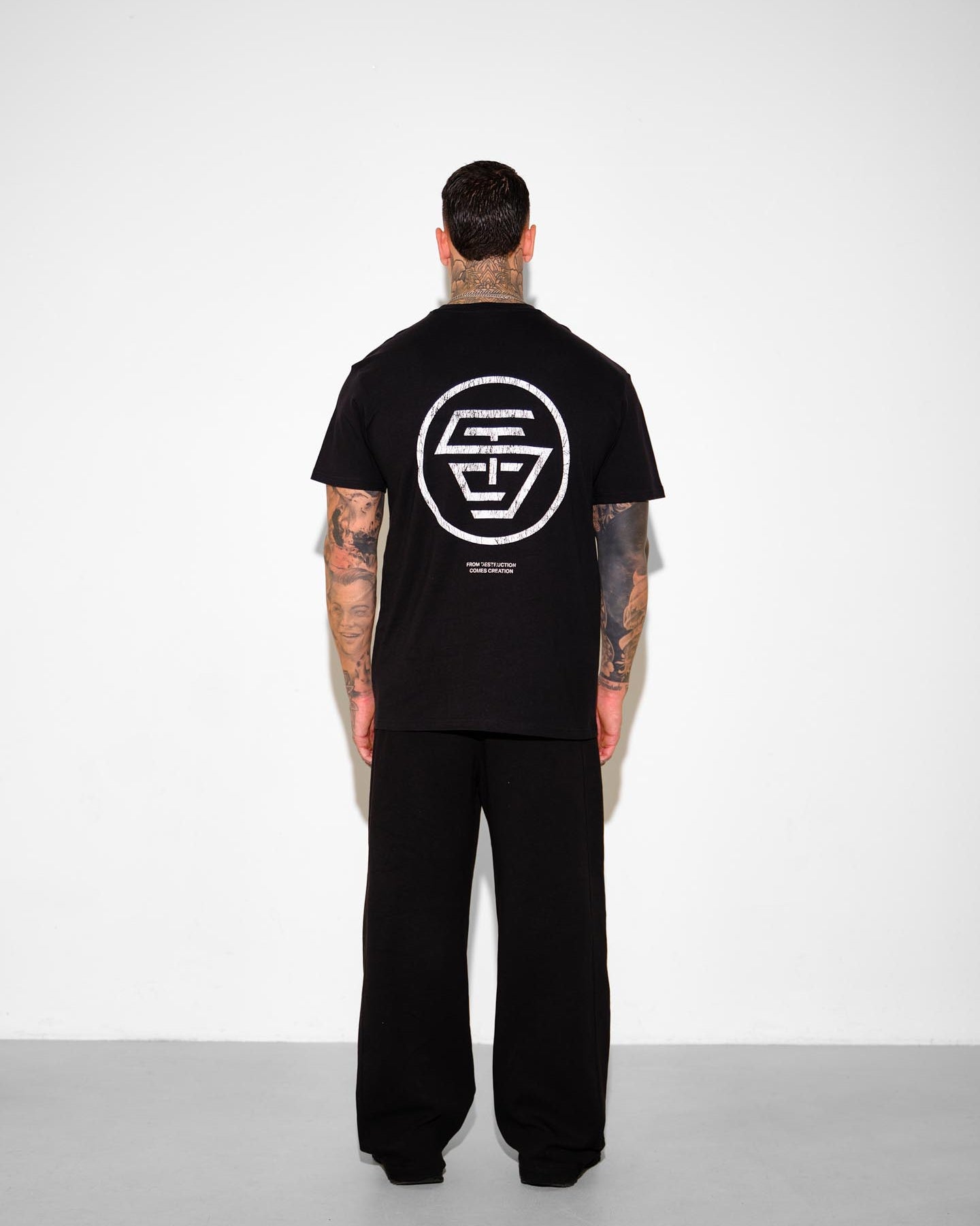 Person wearing a black t-shirt with a logo on the back against a white background