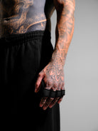 Person with tattoos wearing black grip pads on a gray background