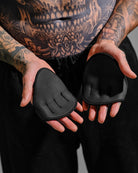 Person with tattoos wearing black grip pads on a gray background