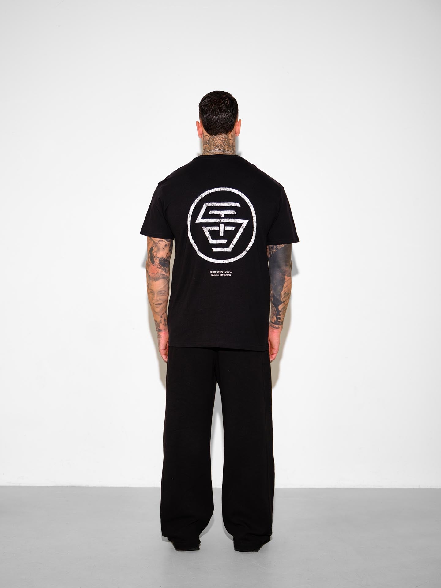 Person wearing a black t-shirt with a logo on the back against a white background