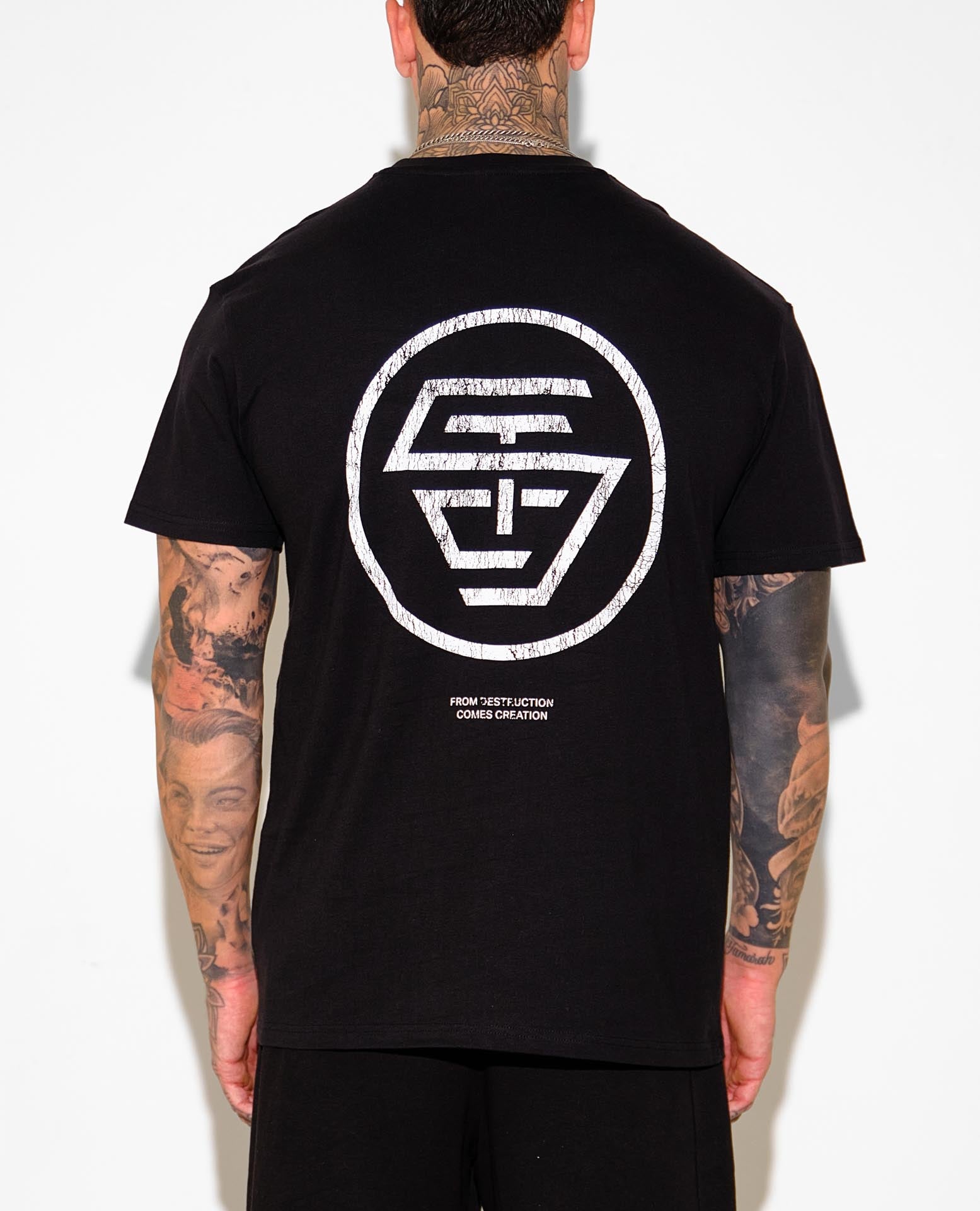 Person wearing a black t-shirt with a white logo on the back, standing against a plain background.