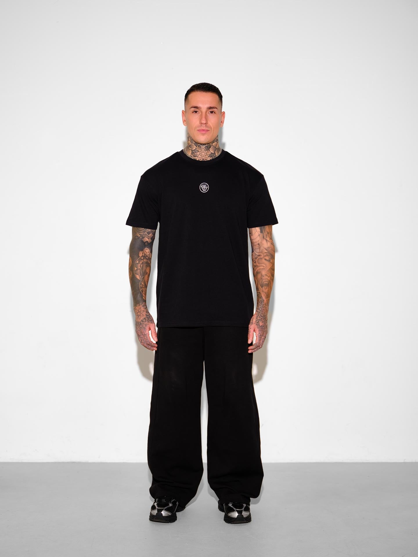 Person wearing a black t-shirt and pants with a white background