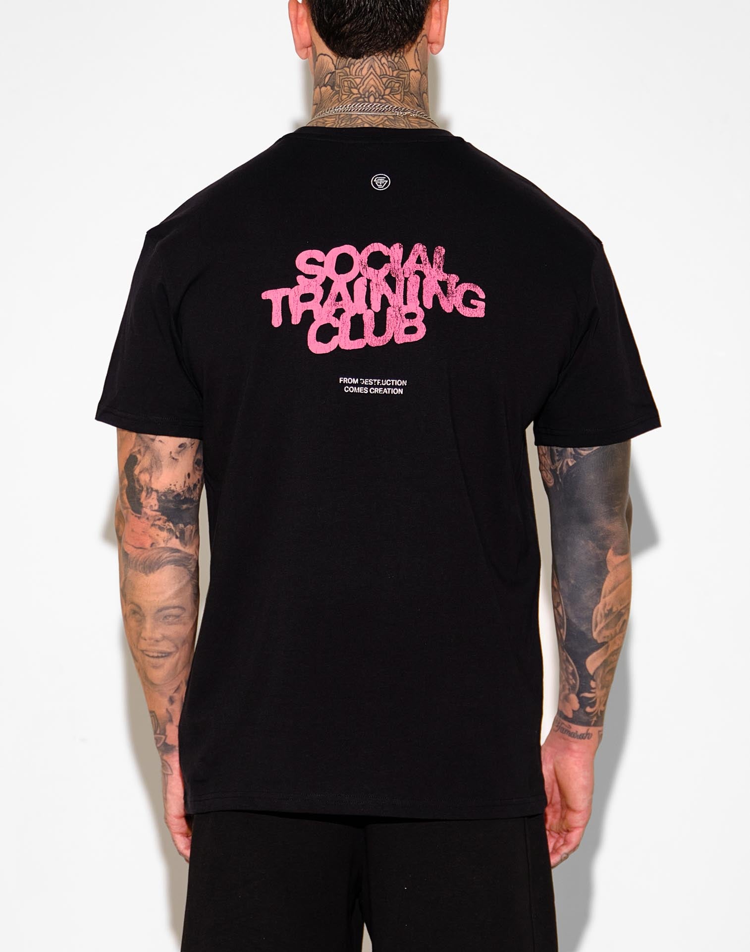 Person wearing a black t-shirt with 'Social Training Club' text on the back, standing against a white background.